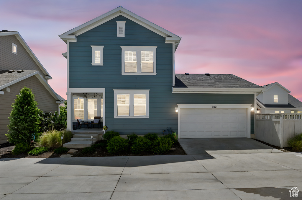 Traditional home with driveway, a porch, and an attached garage