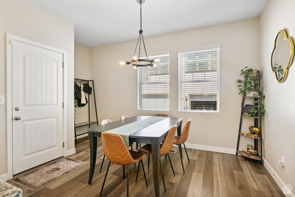 Dining space with wood finished floors, a chandelier, and baseboards