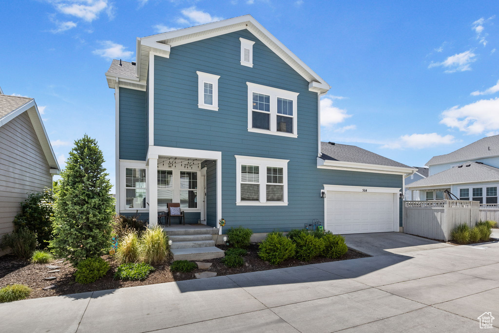 Traditional home featuring a porch, concrete driveway, an attached garage, and roof with shingles