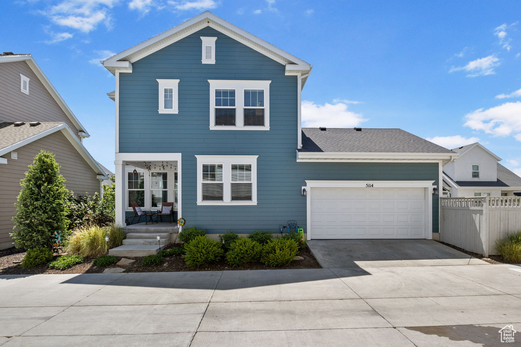 Traditional home with concrete driveway, a garage, and covered porch