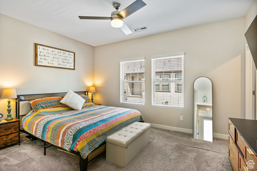Bedroom with light carpet, baseboards, and ceiling fan