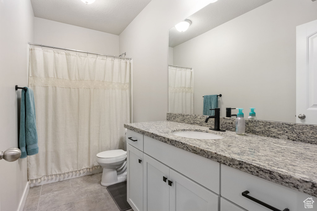 Bathroom featuring vanity, toilet, a shower with curtain, and tile patterned floors