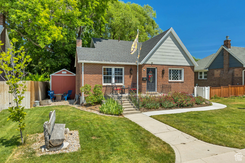 View of front of house featuring brick siding and a chimney