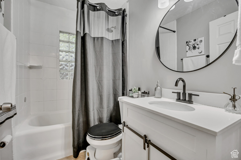 Full bath with toilet, shower / bath combo with shower curtain, and vanity