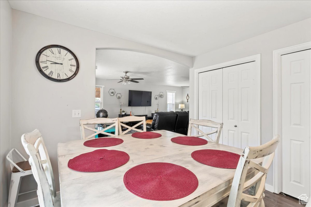 Dining space with a ceiling fan, dark wood-style floors, and arched walkways