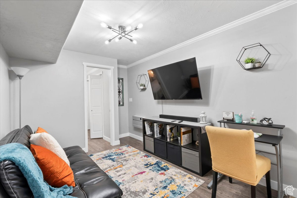 Living area with wood finished floors, baseboards, a chandelier, and ornamental molding