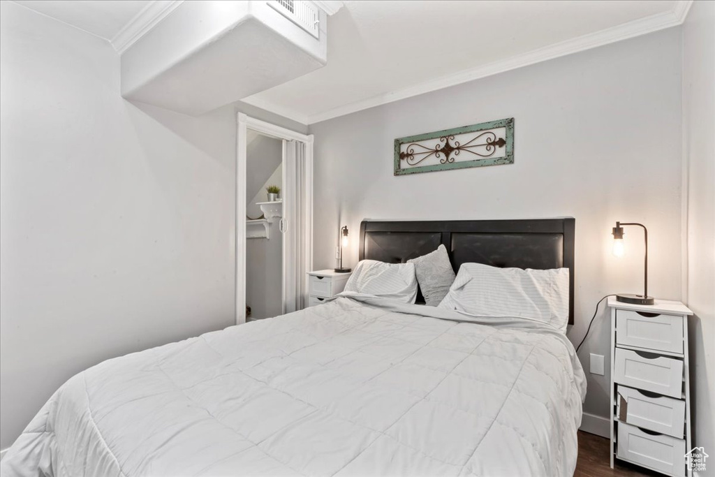 Bedroom featuring crown molding and dark wood-style flooring