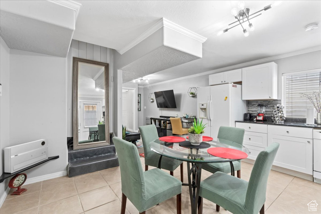 Dining room featuring ornamental molding, light tile patterned floors, baseboards, and a chandelier