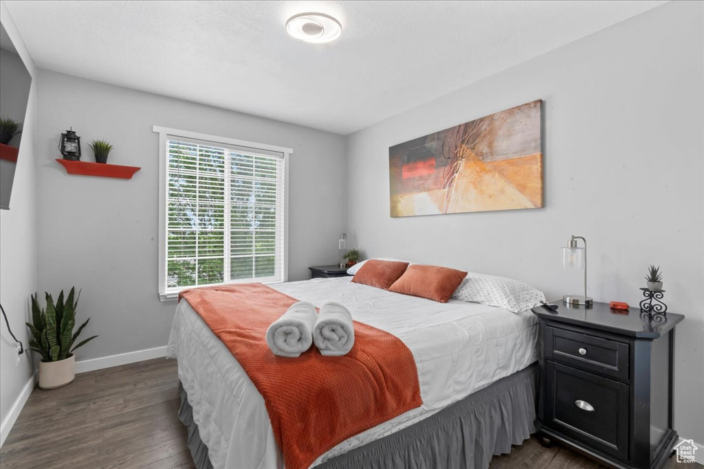 Bedroom with dark wood-style floors and baseboards