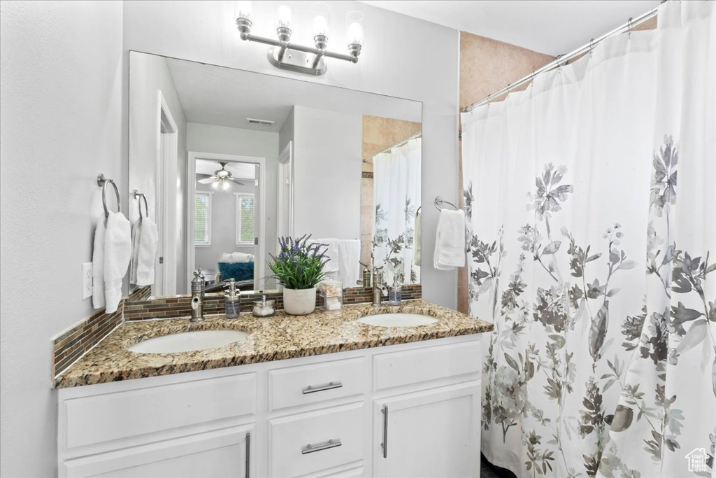 Full bathroom featuring double vanity, curtained shower, and a ceiling fan