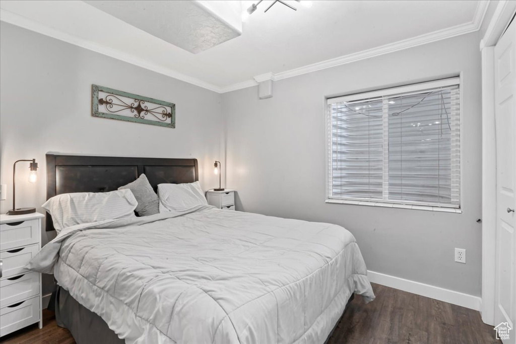 Bedroom with ornamental molding, dark wood-style floors, and baseboards