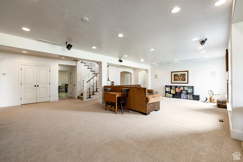 Carpeted living room with stairs, recessed lighting, and baseboards