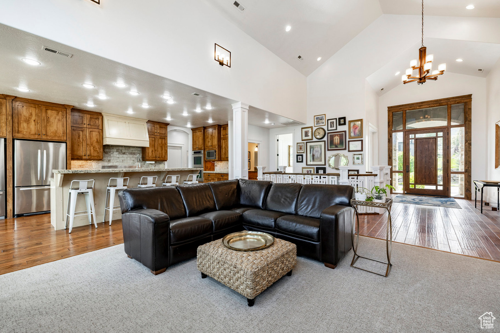 Living area featuring wood finished floors, a chandelier, recessed lighting, decorative columns, and high vaulted ceiling