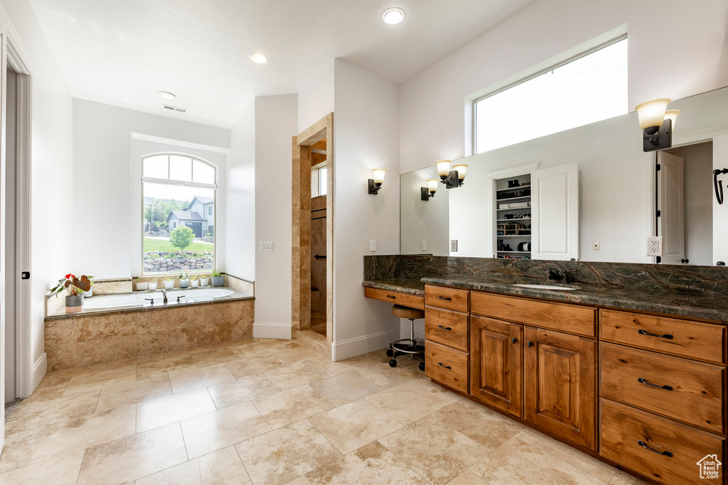 Bathroom featuring a garden tub, vanity, a shower stall, recessed lighting, and baseboards