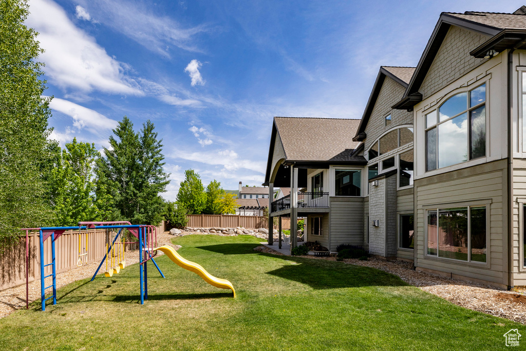 View of yard featuring a playground and a balcony