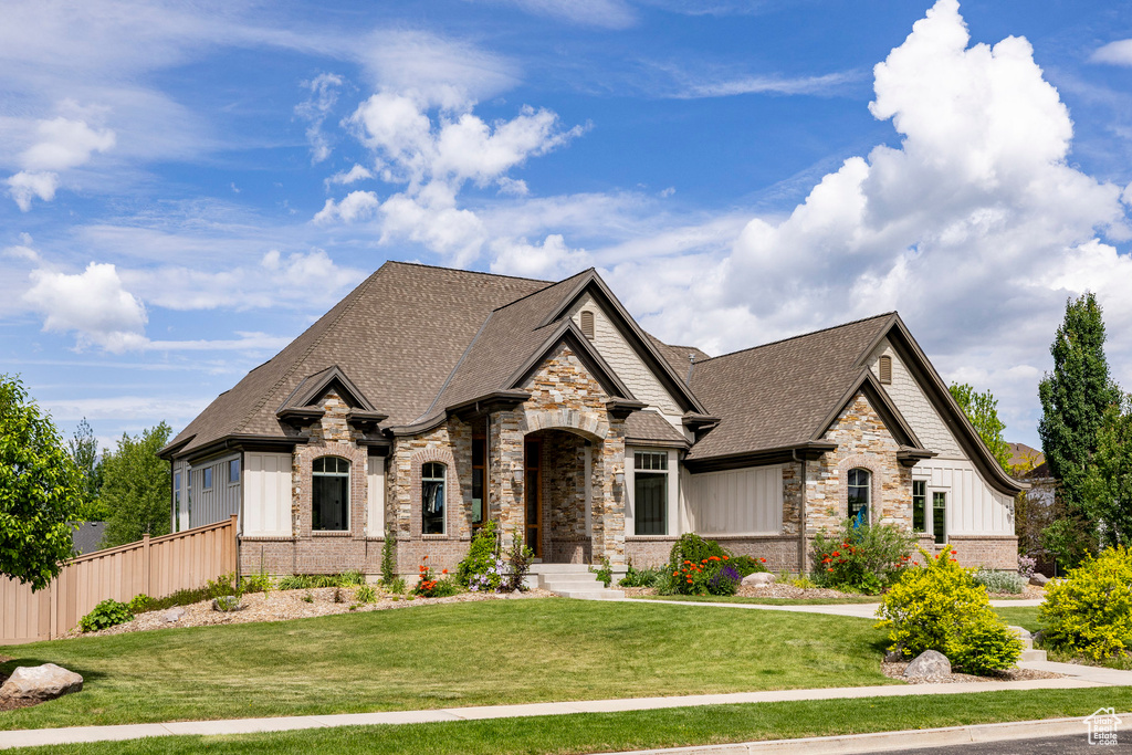 French country inspired facade featuring roof with shingles, stone siding, and board and batten siding