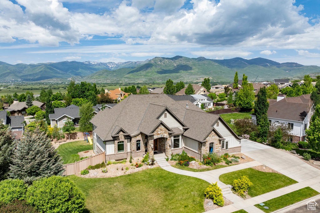 View of front of property with stone siding, a residential view, a mountain view, a shingled roof, and driveway