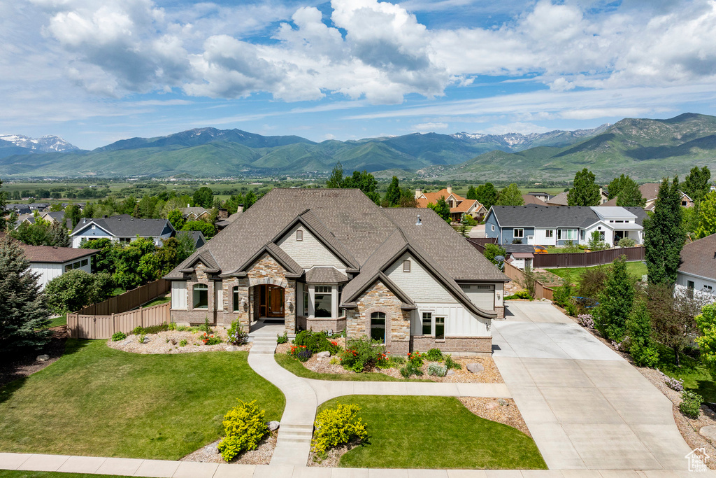 French country inspired facade featuring stone siding, a mountain view, a residential view, a shingled roof, and concrete driveway