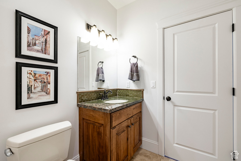 Bathroom featuring vanity, toilet, decorative backsplash, and baseboards