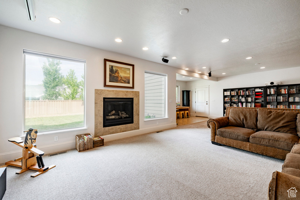 Carpeted living room featuring recessed lighting, plenty of natural light, baseboards, and a tiled fireplace