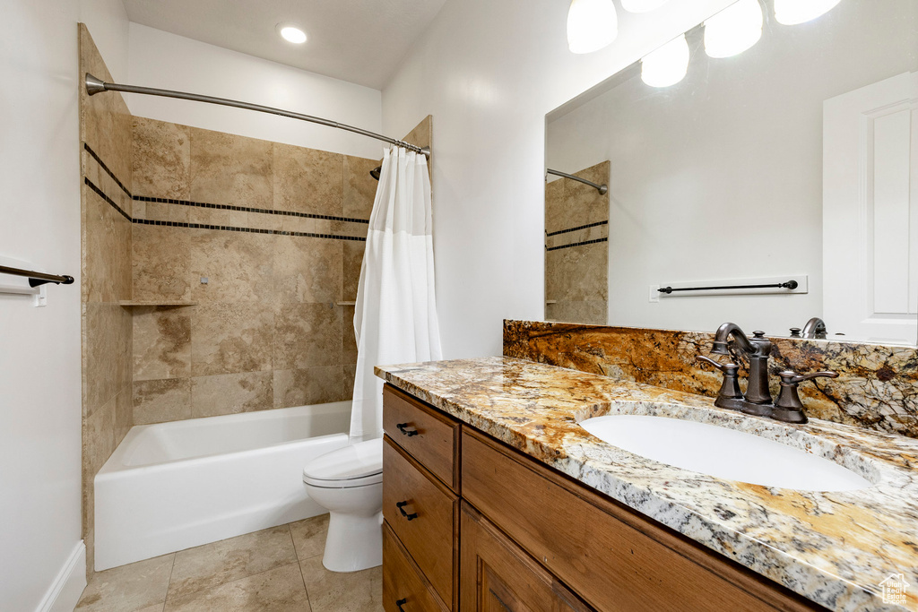 Full bath with vanity, shower / tub combo, toilet, tile patterned floors, and baseboards