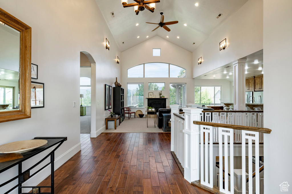 Hallway with dark wood finished floors, high vaulted ceiling, recessed lighting, arched walkways, and baseboards
