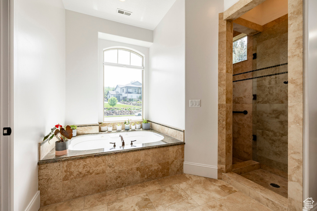 Bathroom with a garden tub, tiled shower, and baseboards