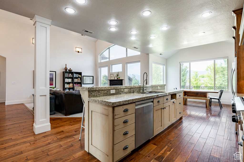Kitchen featuring appliances with stainless steel finishes, a sink, decorative columns, dark wood-type flooring, and recessed lighting