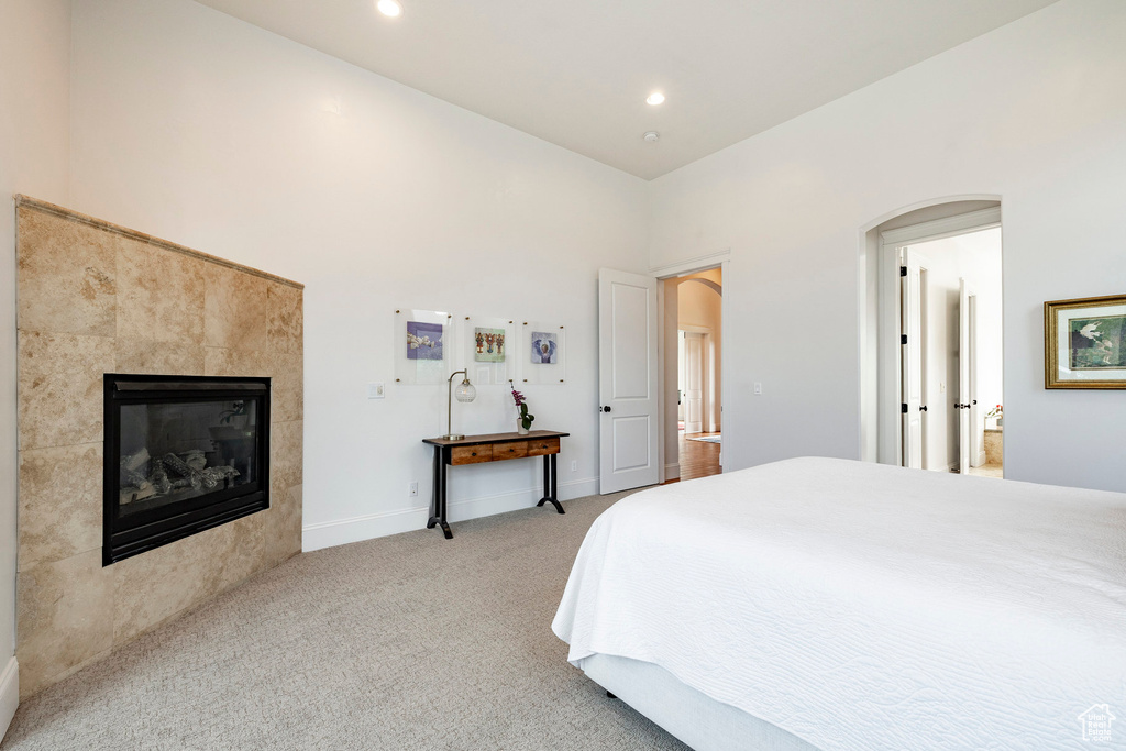Bedroom featuring arched walkways, light colored carpet, a fireplace, recessed lighting, and baseboards