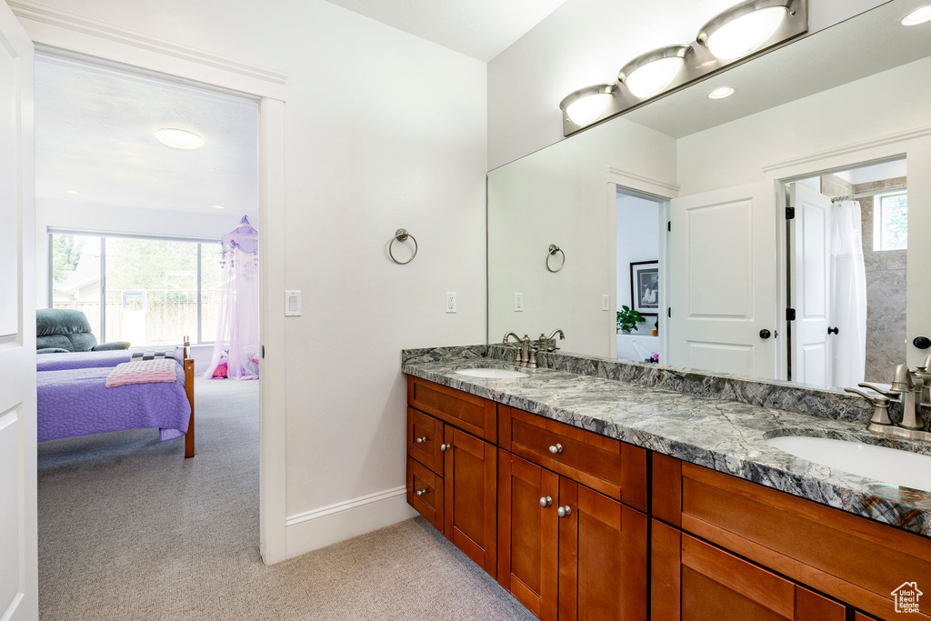 Bathroom featuring ensuite bathroom, double vanity, and baseboards