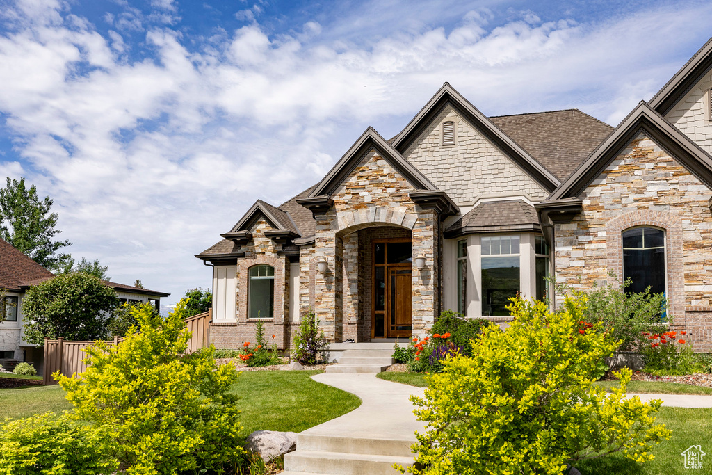 View of front facade featuring stone siding, a shingled roof, and brick siding