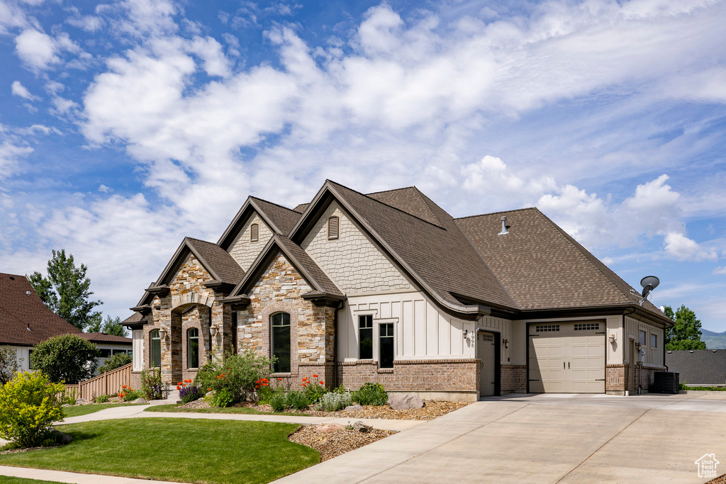View of front of property with a garage, board and batten siding, concrete driveway, central AC, and a shingled roof