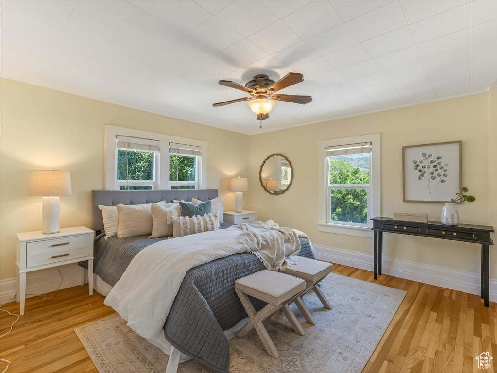 Bedroom with multiple windows, wood finished floors, baseboards, and a ceiling fan
