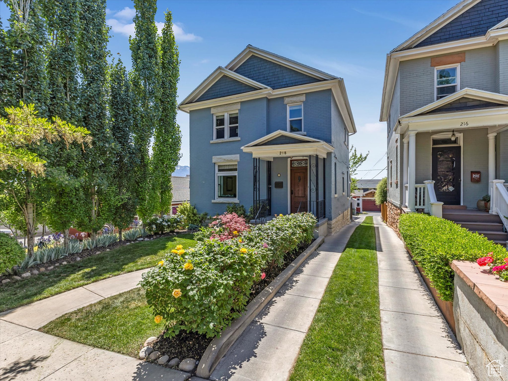 View of front of house featuring brick siding, covered porch, and a front yard