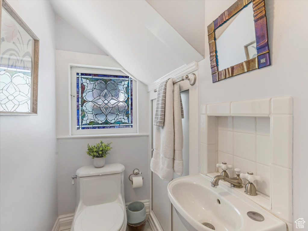 Half bath with toilet, baseboards, and vaulted ceiling