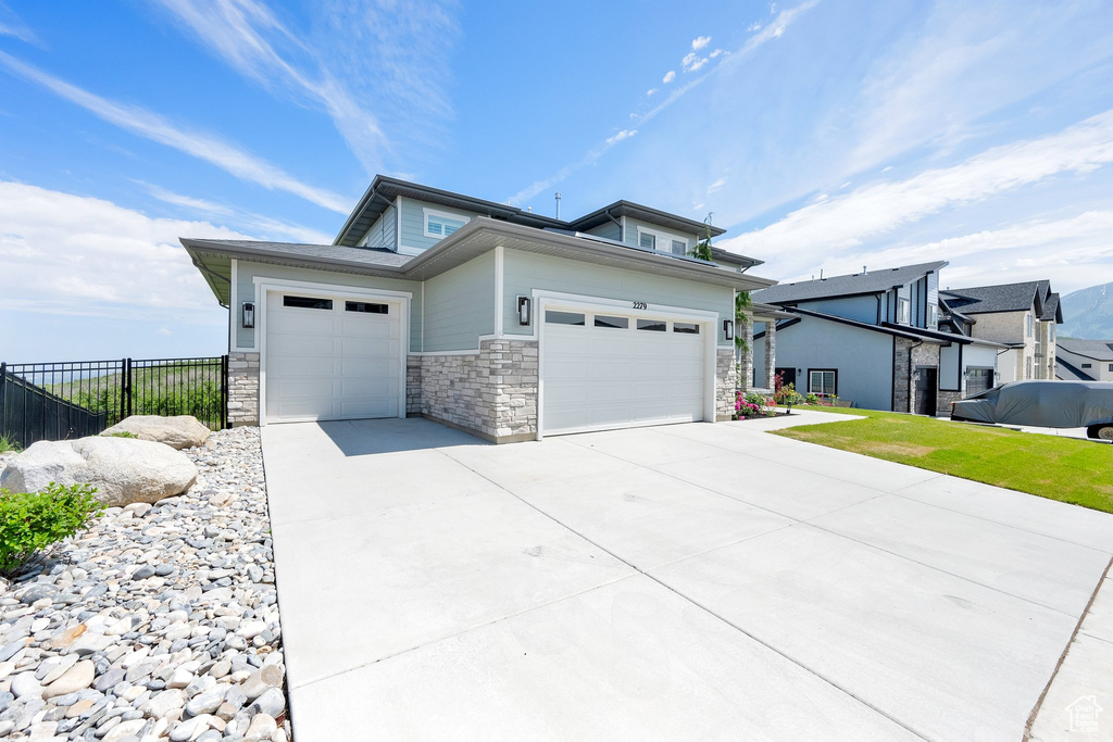View of front of home featuring a garage, concrete driveway, and stone siding