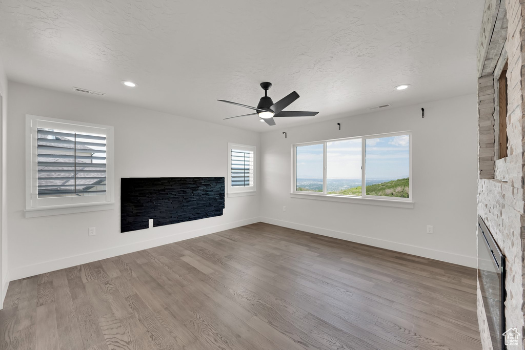 Unfurnished living room with a ceiling fan, baseboards, wood finished floors, recessed lighting, and a textured ceiling