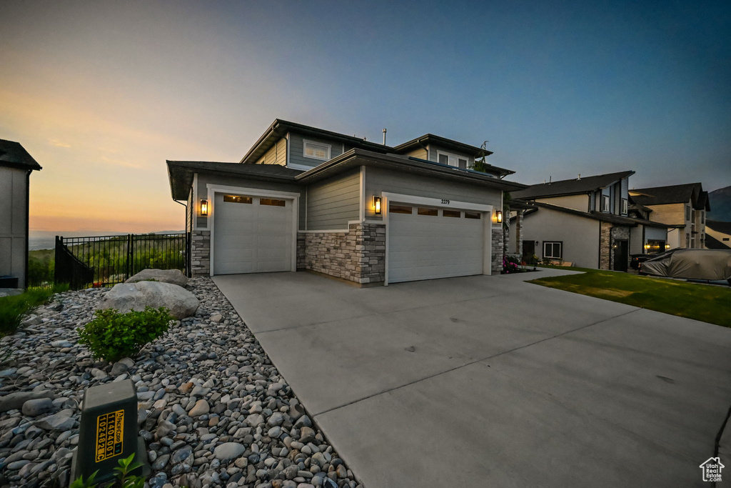 View of front facade featuring a garage, stone siding, and concrete driveway
