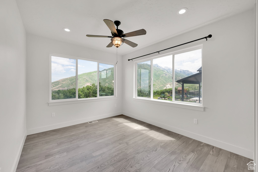 Unfurnished room with baseboards, light wood-style flooring, a ceiling fan, and recessed lighting