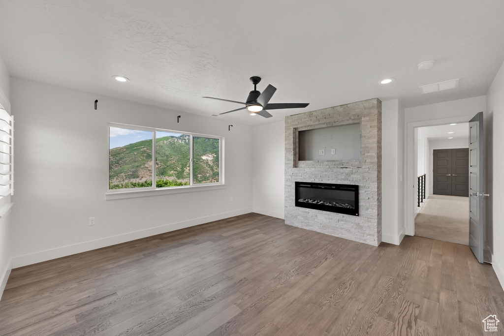 Unfurnished living room with a fireplace, ceiling fan, baseboards, wood finished floors, and recessed lighting