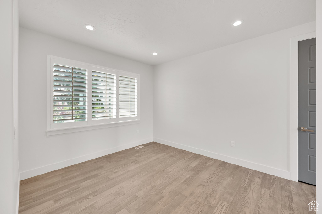 Spare room featuring light wood-style floors, baseboards, and recessed lighting