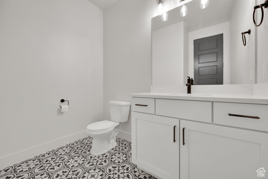 Bathroom featuring baseboards, toilet, vanity, and tile patterned flooring