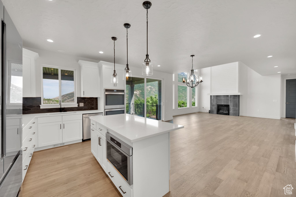 Kitchen featuring stainless steel appliances, a sink, tasteful backsplash, light wood-style floors, and recessed lighting