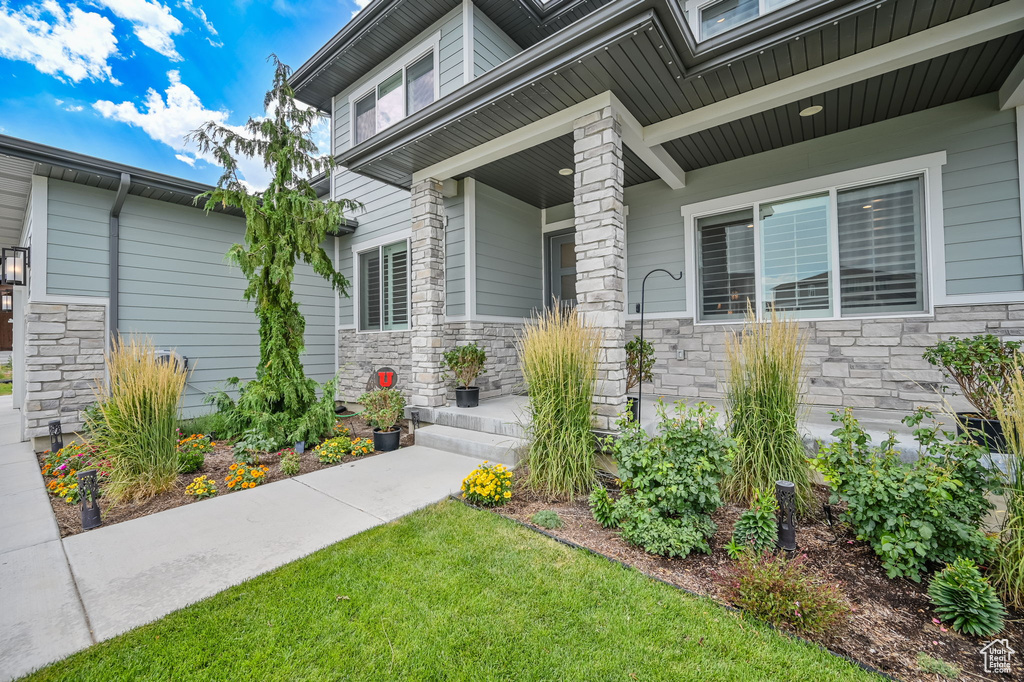 Property entrance with stone siding, covered porch, and a lawn