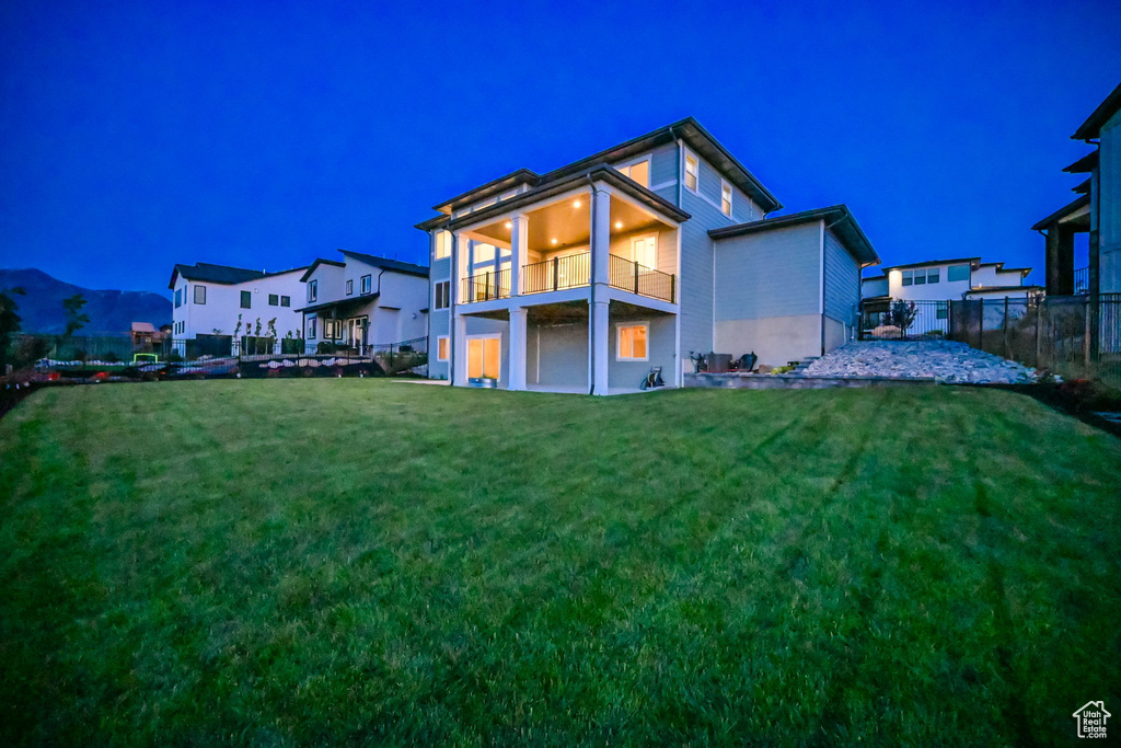 Back of house at night featuring a balcony