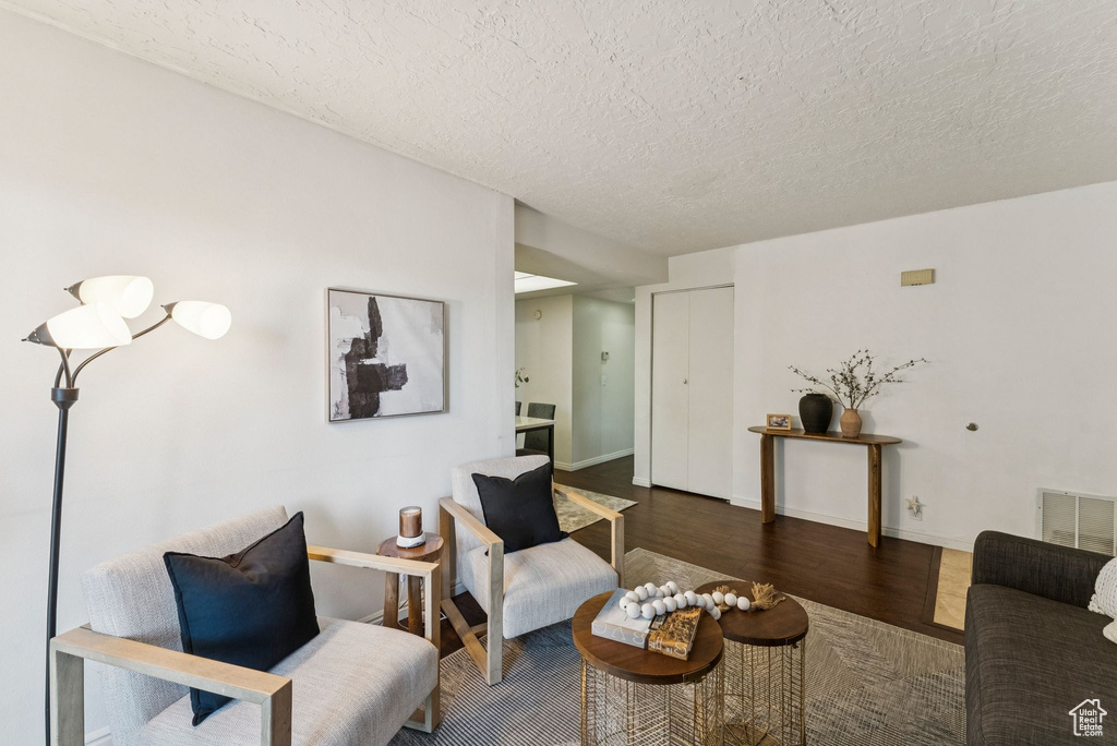 Living room featuring wood finished floors, a textured ceiling, and baseboards