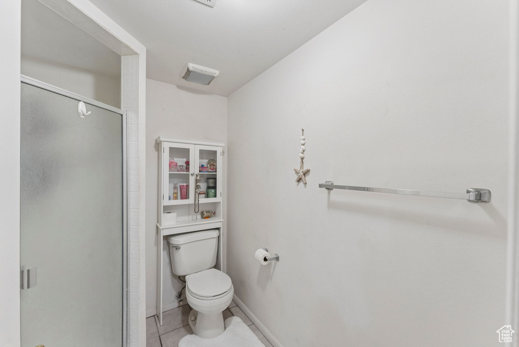 Bathroom featuring a stall shower, toilet, and tile patterned flooring