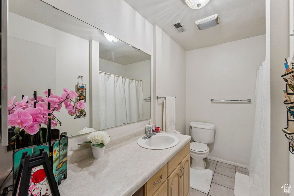 Full bathroom with vanity, toilet, tile patterned floors, and baseboards