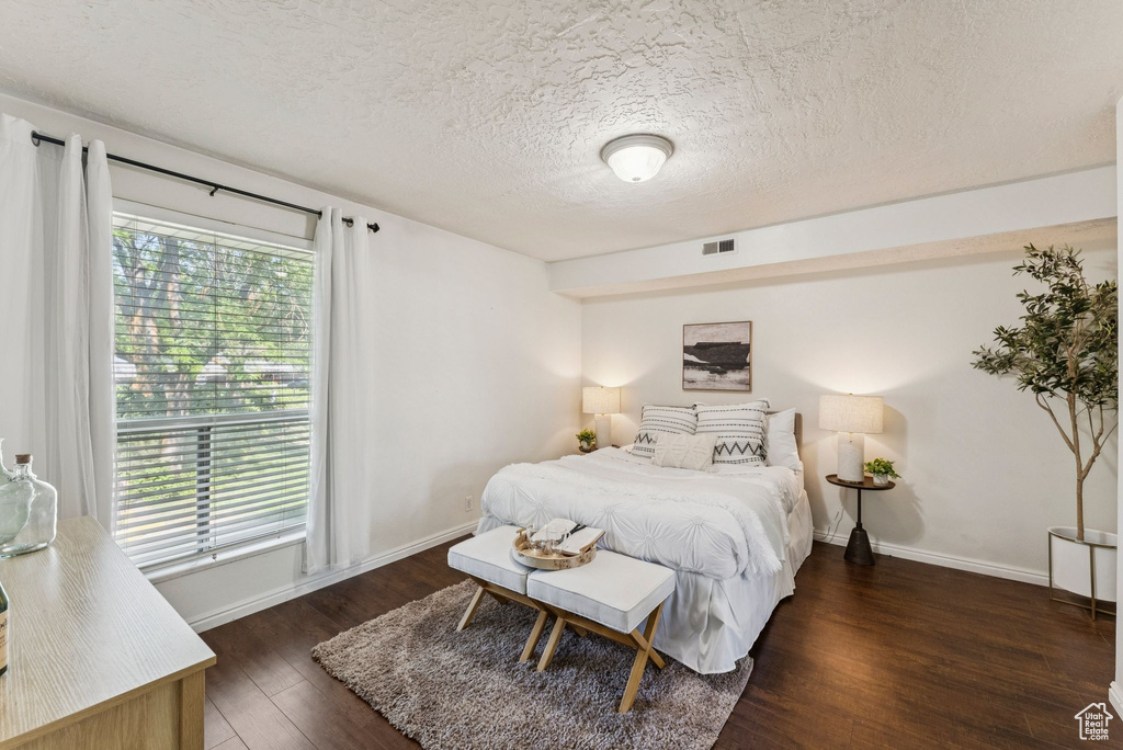 Bedroom with wood finished floors, a textured ceiling, and baseboards