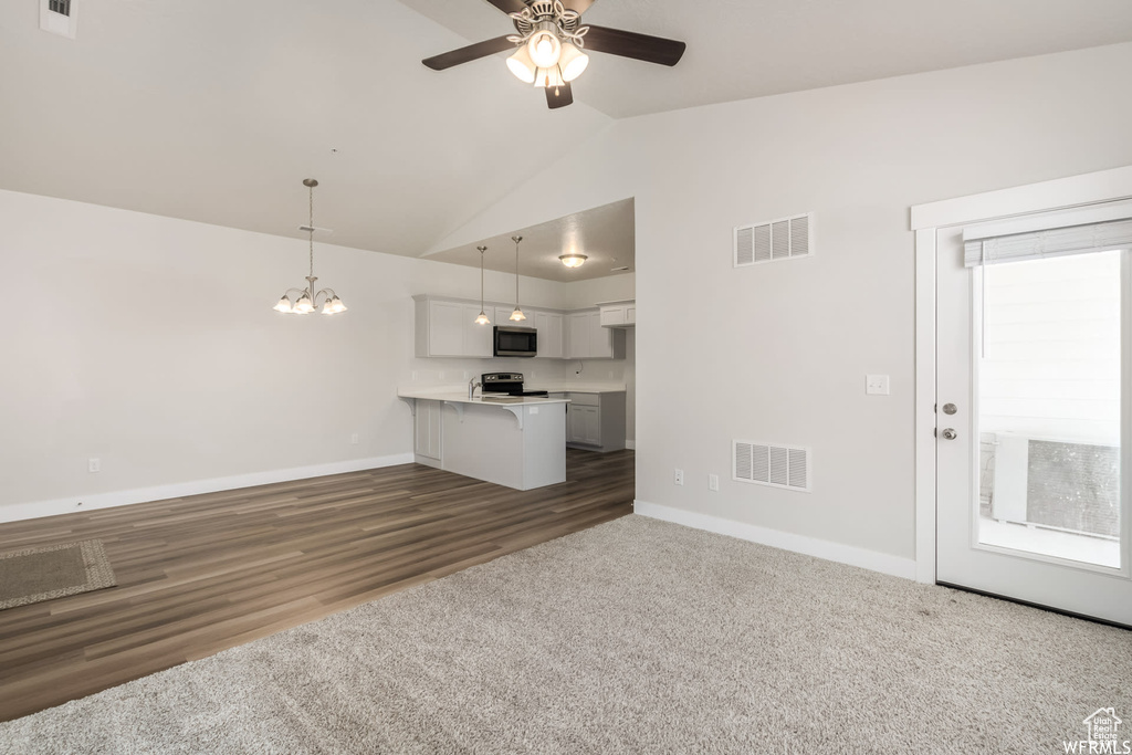 Unfurnished living room featuring baseboards, ceiling fan, a chandelier, carpet floors, and high vaulted ceiling